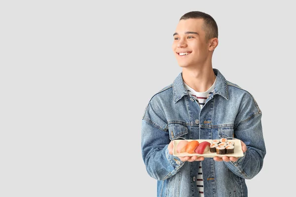 軽い背景でおいしい寿司を持つ若い男 — ストック写真