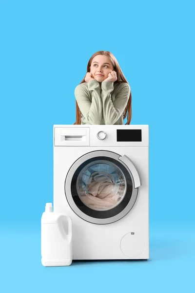 파란색 배경에 세탁기에 기대는 — 스톡 사진