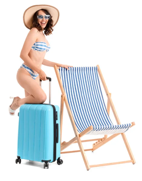 Young woman with suitcase and deck chair on white background
