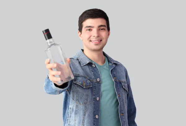 軽い背景にウォッカのボトルを持っている若い男 — ストック写真