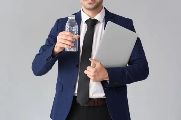 Jovem Empresário Com Garrafa Água Laptop Fundo Cinza — Fotografia de Stock