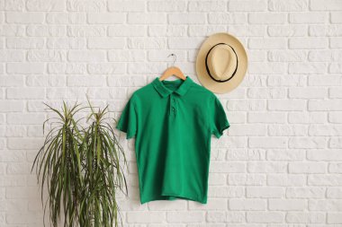 Beyaz tuğla duvarda asılı şık yeşil tişört ve şapka