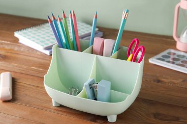 Ahşap masada farklı kırtasiye malzemesi olan tutucu.