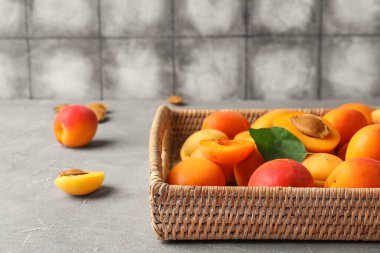 Gri masada tatlı kayısıları olan hasır kutu.