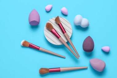 Mavi arkaplanda makyaj süngerleri ve fırçalar