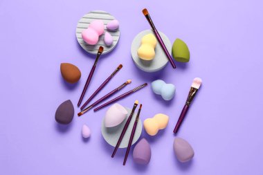Dekoratif podyumlar makyaj fırçaları ve eflatun arka planda süngerler