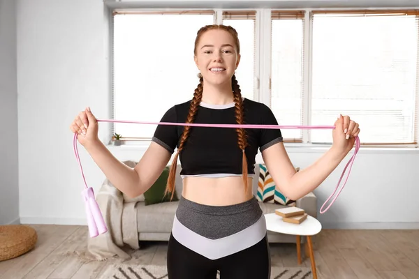 Sporty young woman with skipping rope at home