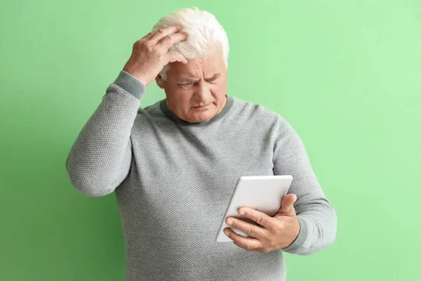 混淆不清的老年人在绿色背景下使用平板电脑 — 图库照片