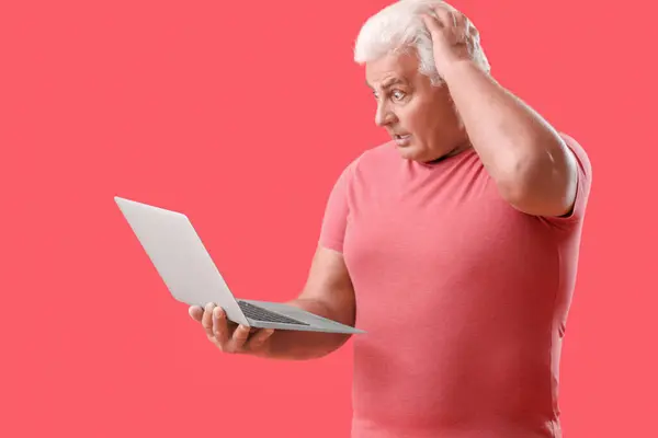 用红色背景的笔记本电脑吓到了老年人 — 图库照片