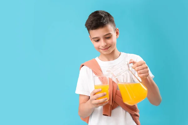 Mały Chłopiec Wlewający Sok Pomarańczowy Szklanki Niebieskim Tle — Zdjęcie stockowe