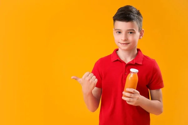 Mały Chłopiec Butelką Soku Pomarańczowego Wskazując Coś Tle Koloru — Zdjęcie stockowe