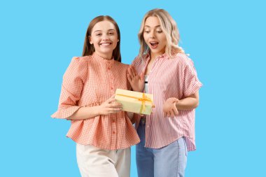 Mavi arka planda hediyeleri olan genç kardeşler.