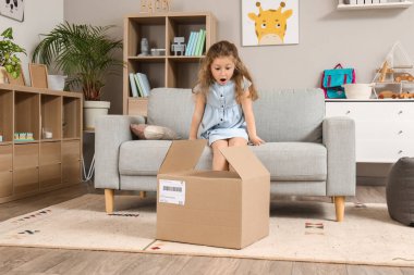 Şok olmuş küçük kız paketini evde açıyor.