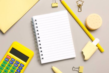 Gri arkaplanda farklı kırtasiye malzemesi bulunan defter