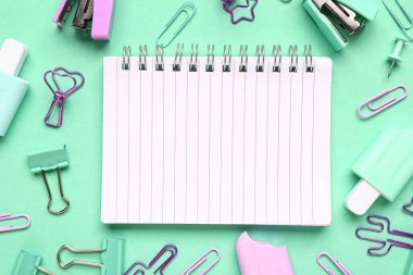 Turkuaz arka planda farklı kırtasiye malzemesi içeren defter