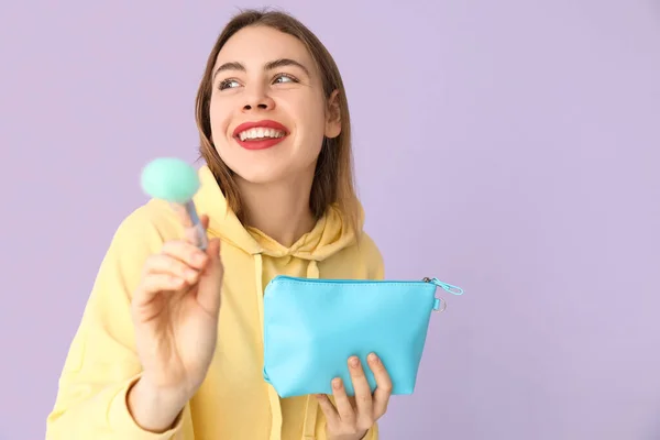 Junge Frau Mit Kosmetiktasche Und Make Pinsel Auf Fliederfarbenem Hintergrund — Stockfoto