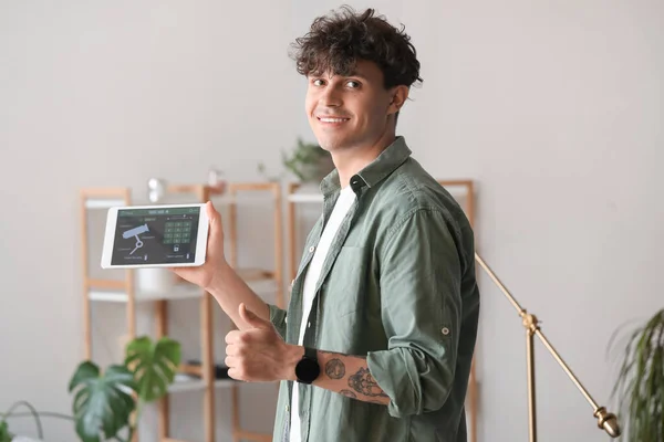 Young man with smart home security system control panel showing thumb-up
