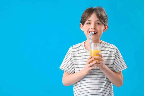 Mały Chłopiec Pijący Sok Pomarańczowy Niebieskim Tle — Zdjęcie stockowe