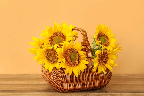 Wicker basket with beautiful sunflowers on wooden table