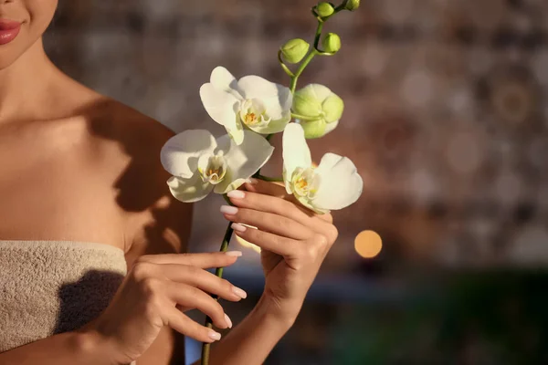 スパサロン クローズアップで蘭花を持つかなり若い女性 — ストック写真