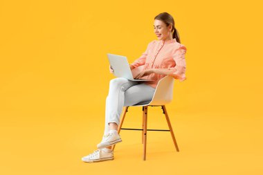 Sarı arka planda dizüstü bilgisayarla çalışan kadın programcı