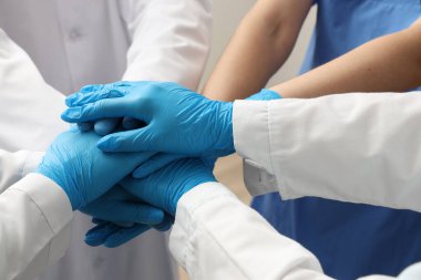 Tıbbi eldivenli doktorlar klinikte el ele tutuşuyorlar.