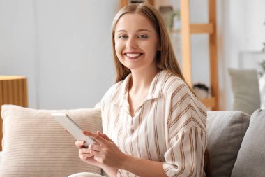 Evde tablet bilgisayarla çalışan genç bir kadın.