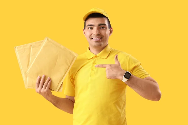 Mensajero Masculino Señalando Sobres Sobre Fondo Amarillo — Foto de Stock