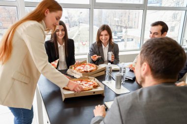 Ofisinde lezzetli pizzaları olan bir grup iş adamı.