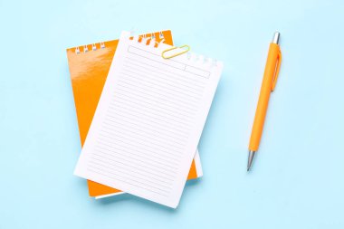 Mavi zemin üzerinde ataç ve kalem olan kağıt sayfası