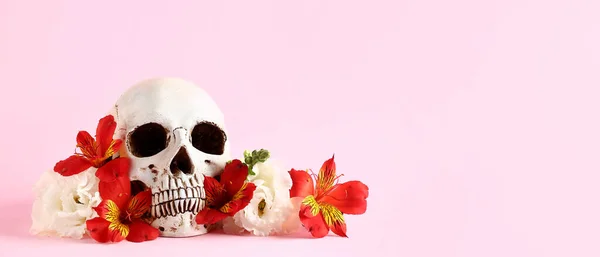 テキスト用のスペースを持つピンクの背景に美しい花を持つ人間の頭蓋骨 — ストック写真