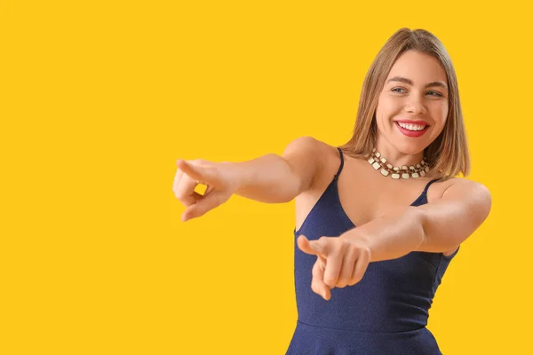 Mladá Žena Náhrdelníkem Ukazuje Něco Žlutém Pozadí — Stock fotografie
