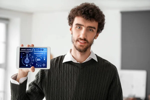 Young man with smart home security system control panel in kitchen