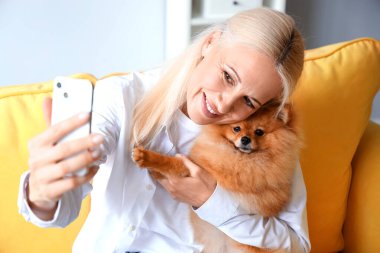 Pomeranya köpekli olgun bir kadın evde selfie çekiyor, yakın plan.