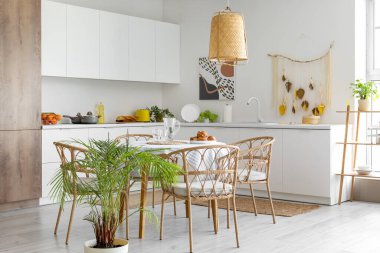 Modern mutfak, yemek masası ve beyaz tezgahlar.