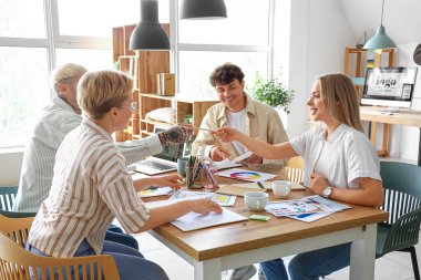Ofisteki masada renk paletleri ile çalışan grafik tasarımcı takımı
