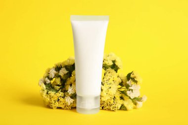 Kozmetik ürünler ve sarı arka planda güzel çiçekler.