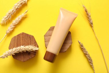 Kozmetik ürün tübü ve sarı arka planda buğday dikenleri olan bileşim