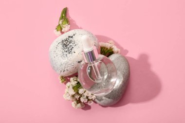 Pembe arka planda gerekli yağ, taş ve çiçekleri içeren kompozisyon