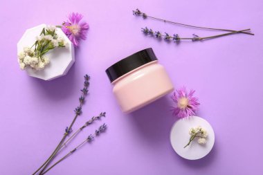 Leylak arka planında kozmetik ürün kavanozu ve çiçeklerle kompozisyon