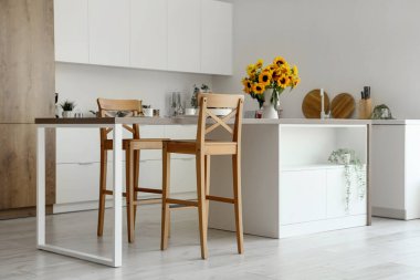 Modern mutfağın içinde vazoda ayçiçekleri var.