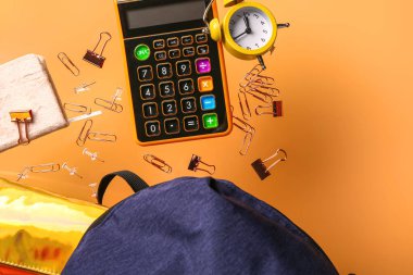 Renkli arka planda uçan kırtasiyeli okul çantası, yakın plan