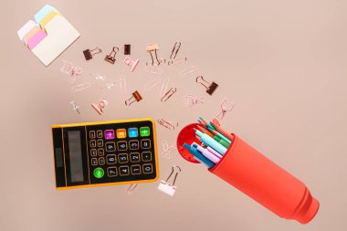 Renk arkaplan üzerinde uçan farklı kırtasiye ve hesap makinesine sahip kalem kutusu