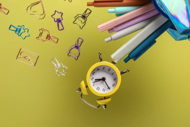 Renk arkaplan üzerinde farklı kırtasiye ve alarm saatine sahip kalem kutusu