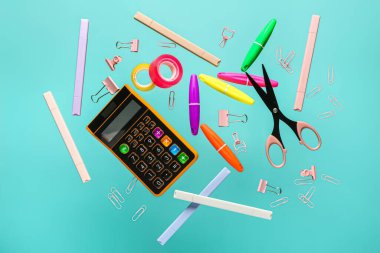 Renk arkaplanı üzerinde uçan kırtasiye ve hesap makinesi