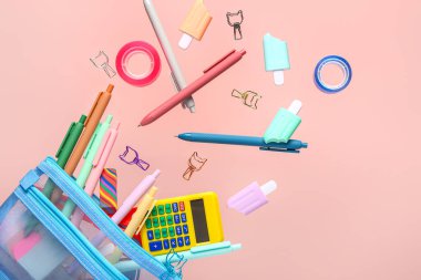 Pembe arka planda farklı kırtasiye malzemesi olan kalem kutusu