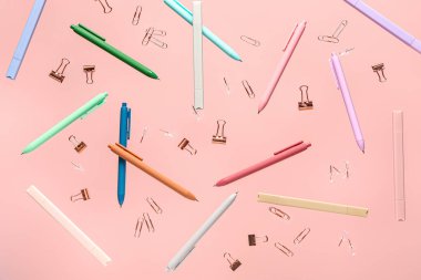 Pembe arka planda uçuşan farklı kırtasiye malzemeleri
