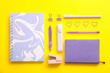 Sarı zemin üzerine farklı okul kırtasiyesi ve not defterleri.