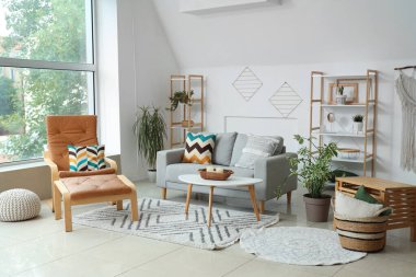 Aydınlık oturma odasının içinde bitkiler, kanepe ve koltuk.