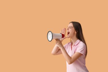 Çığlık atan, turuncu arka planda megafonu olan genç ve güzel bir kadın.